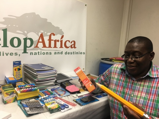 Sylvester, the CEO of Develop Africa with the donated school supplies