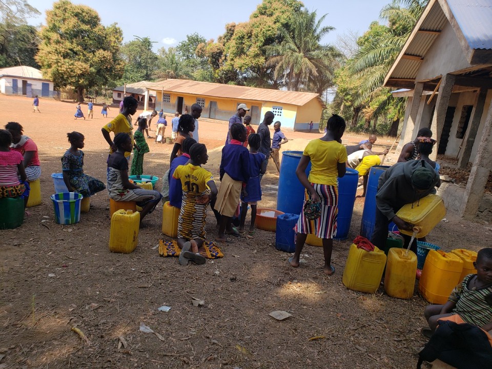 Kamawornie community bringing in water for construction of the nursery classrooms