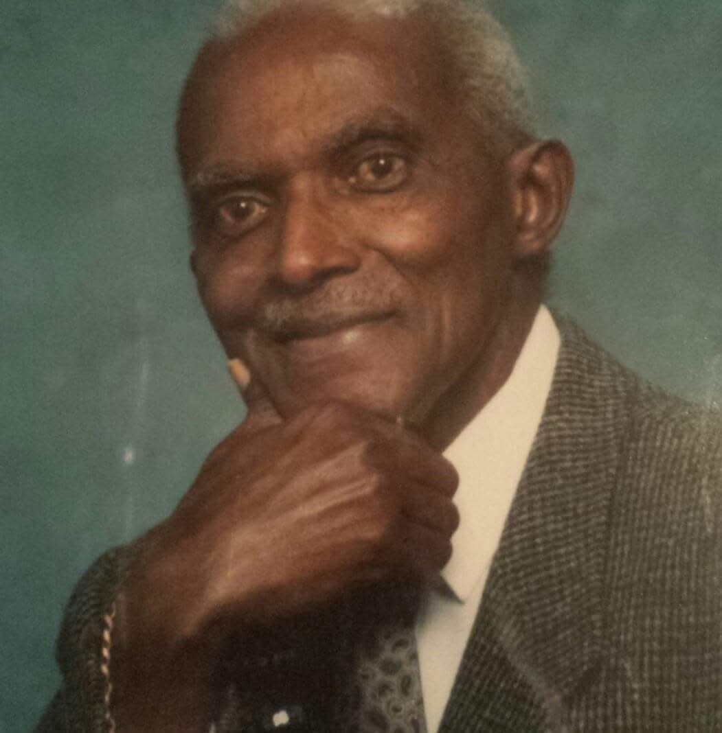 Rev. Dr. Eustace Lloyd Renner, smiling, hand at his chin