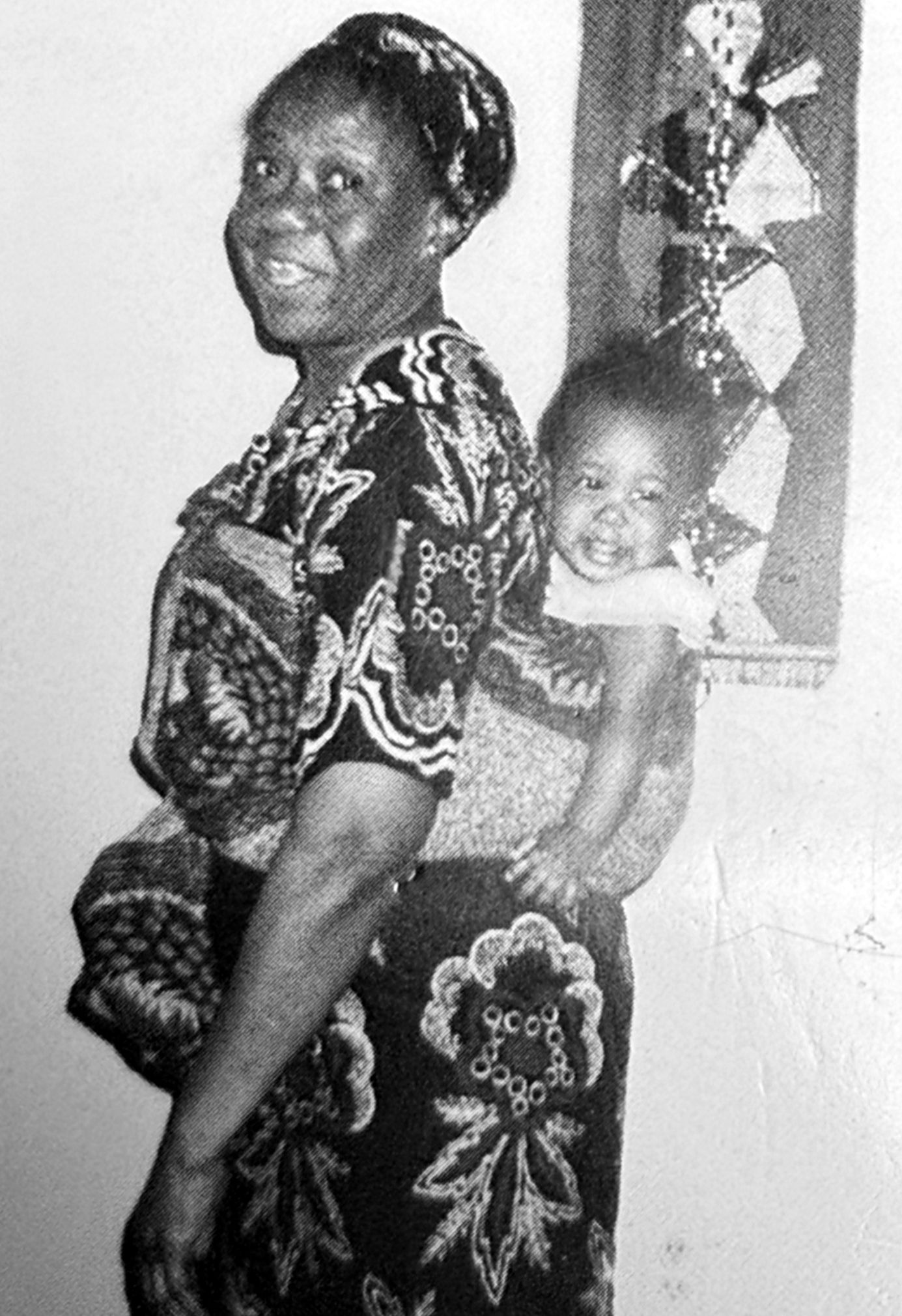 Zainabu Renner carrying a grandchild on her back in a lappa, smiling